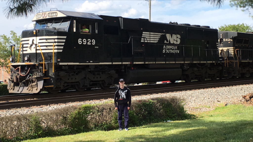 Michael Edwards Poses in Front of a Train