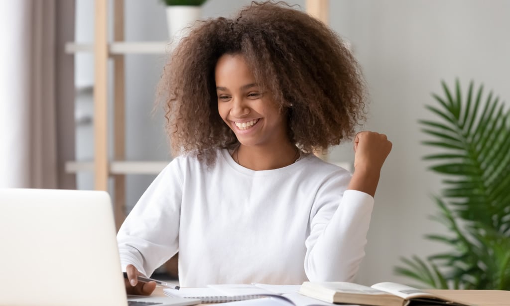 Excited overjoyed african teen girl student winner looking at laptop