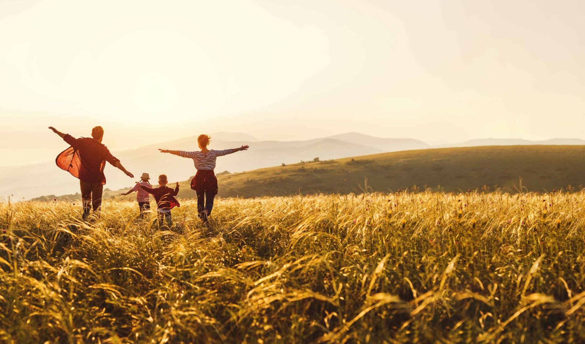 A family running through a beautiful field with their arms outstretched.