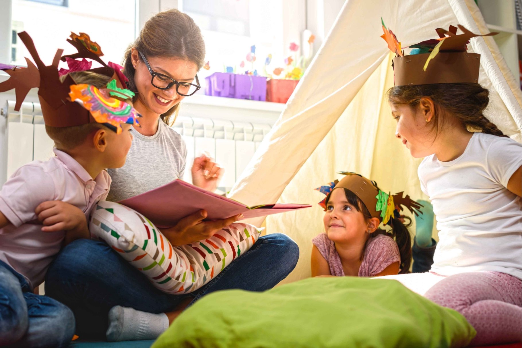 children in a circle listening to a woman reading