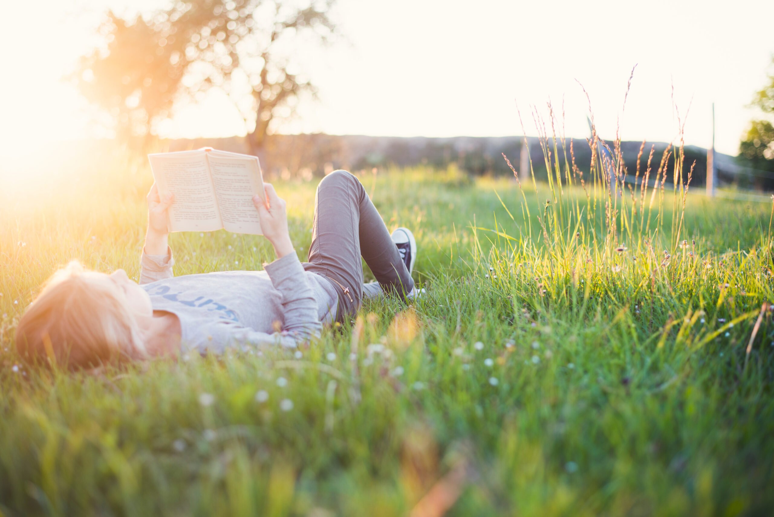 A girl reads a book while lying in the grass