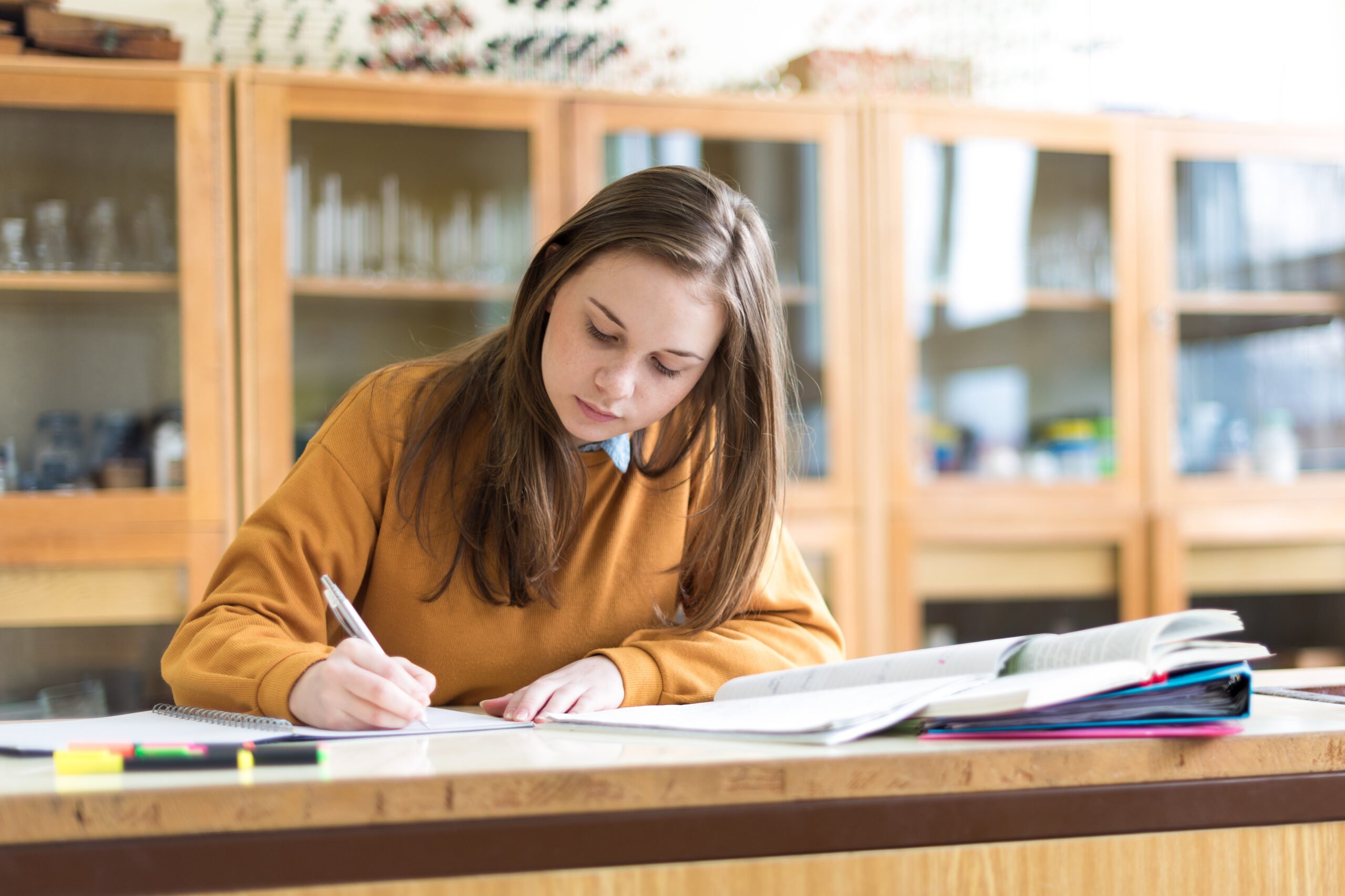 Young female college student in chemistry class, writing notes. Focused student in classroom. Authentic Education concept.