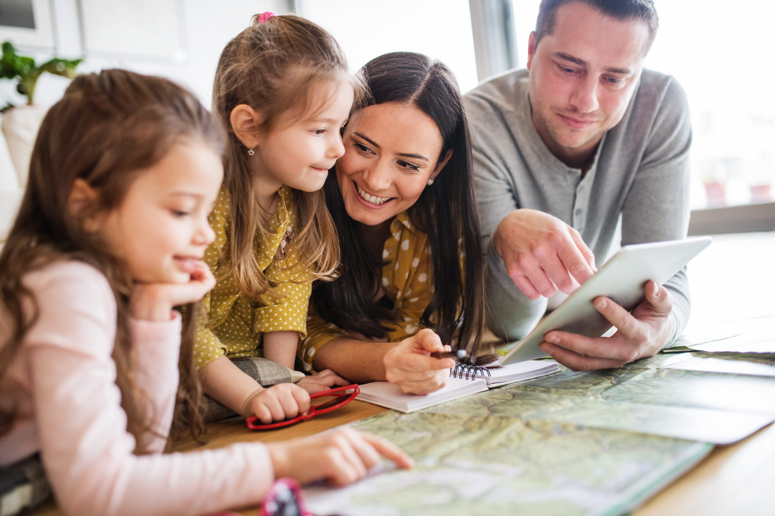 Young happy family with two children and tablet preparing for holiday at home.