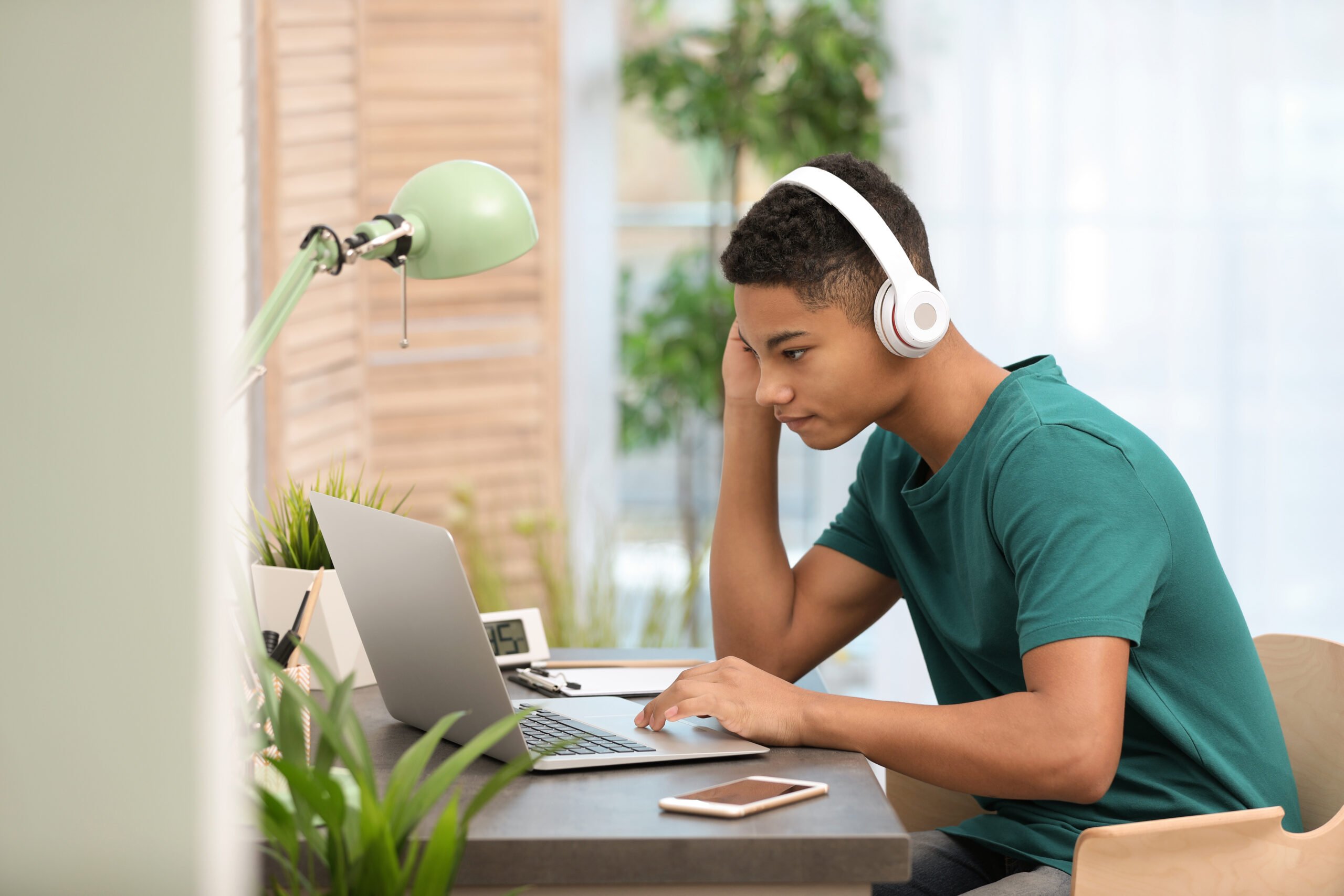 teen boy studying on laptop with headphones