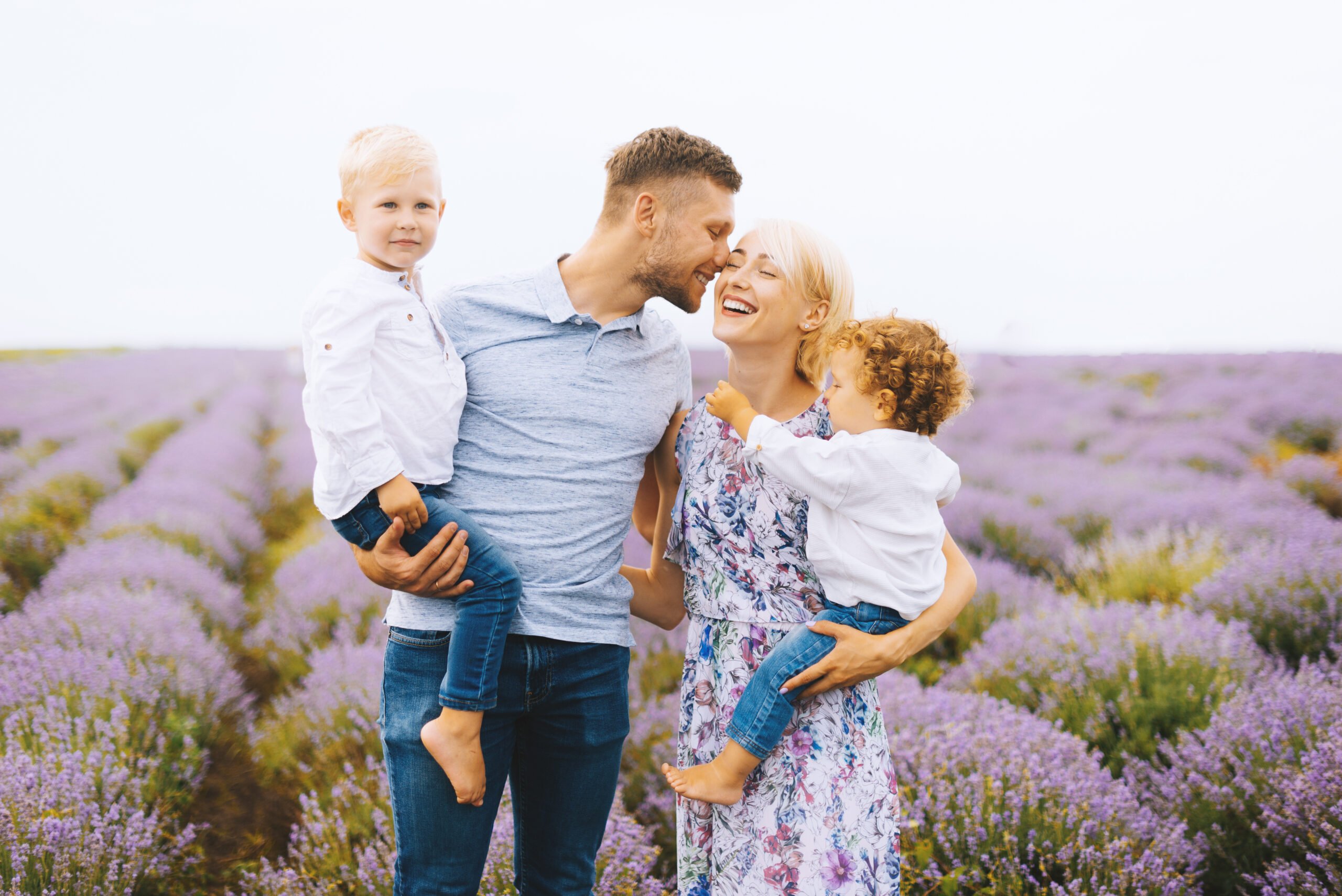 Beautiful portrait of a young family with two baby boys in lavender field. Family love and value concept.