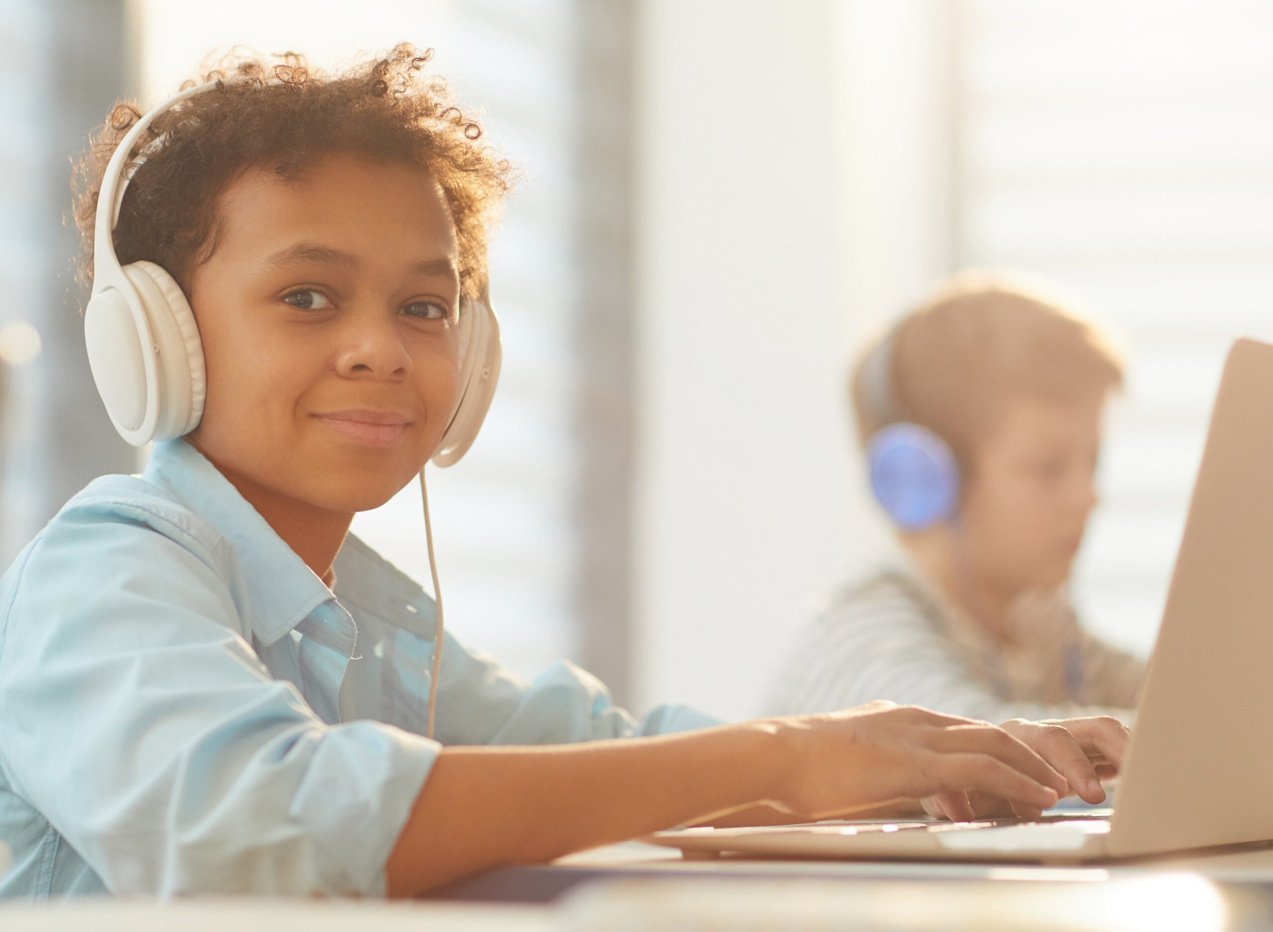 Medium portrait of African American boy wearing headphones using laptop while studying at school, copy space