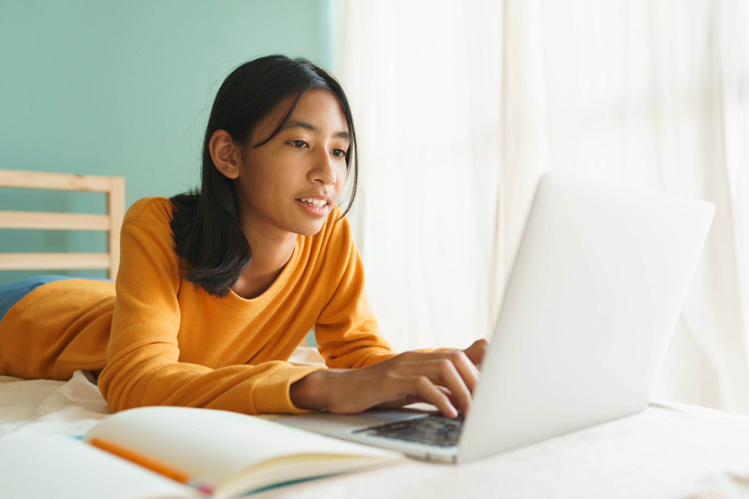 homeschool student laying on her bed doing schoolwork