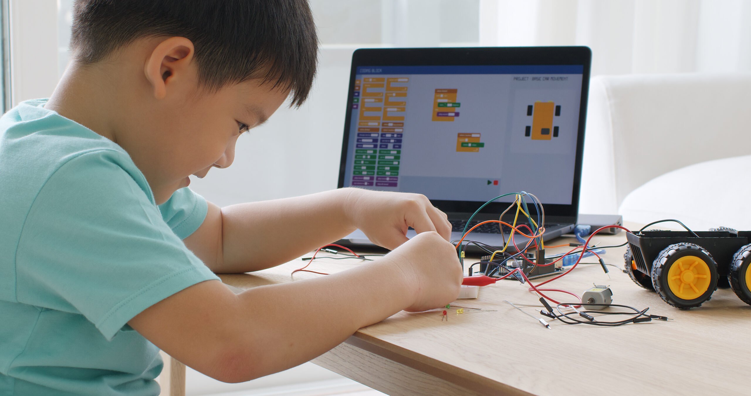 Asia home school young small kid happy smile self study online lesson excited make AI circuit toy. STEM STEAM digital scratch class on laptop screen for active children play arduino enjoy fun hobby.