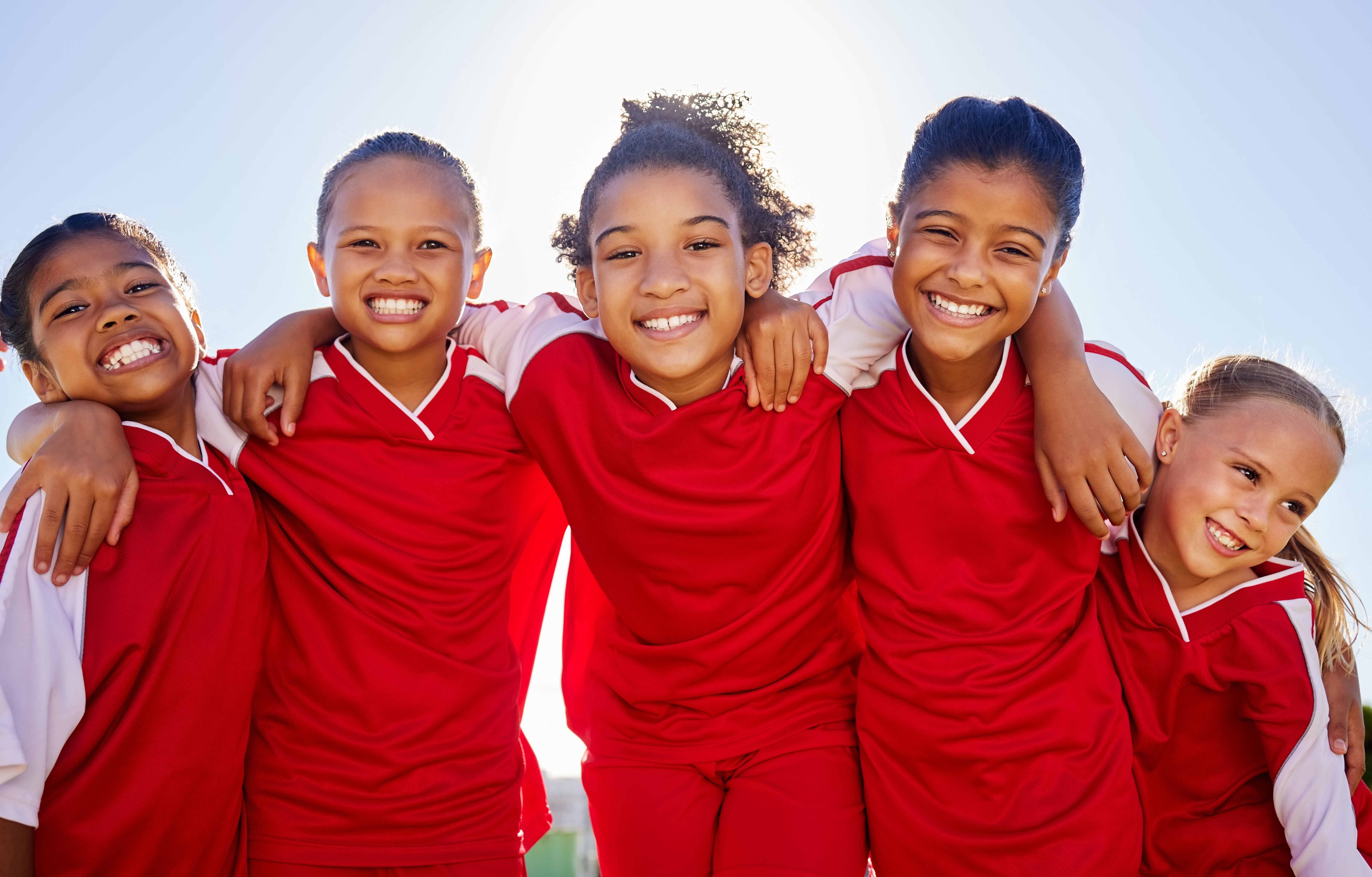 Group portrait, girl football and field with smile, team building motivation or solidarity at sport training. Female kids, sports diversity and happy with friends, teamwork or development for soccer.