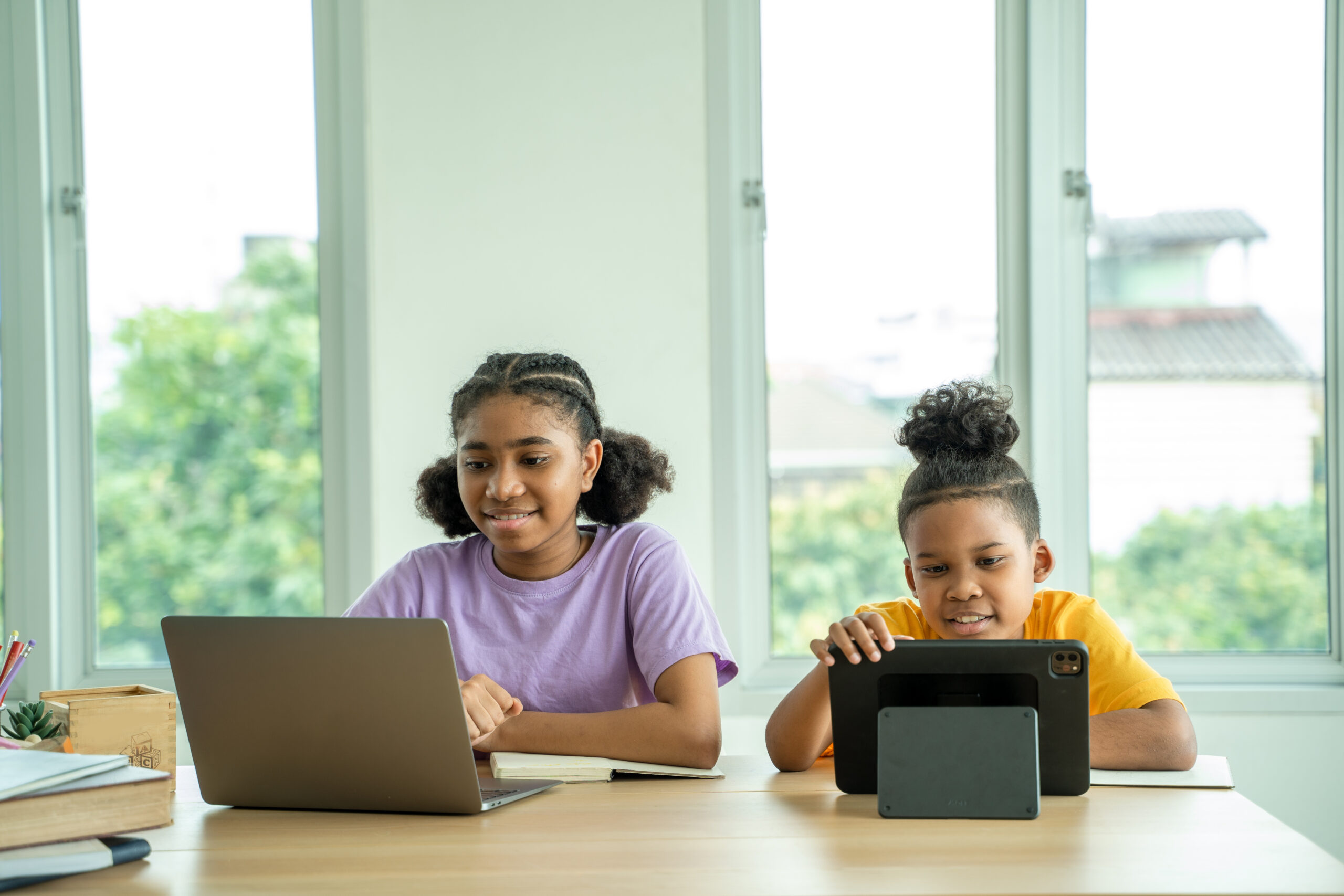 African american elementary school children using digital tablet computer learning online education program app technology during lesson.