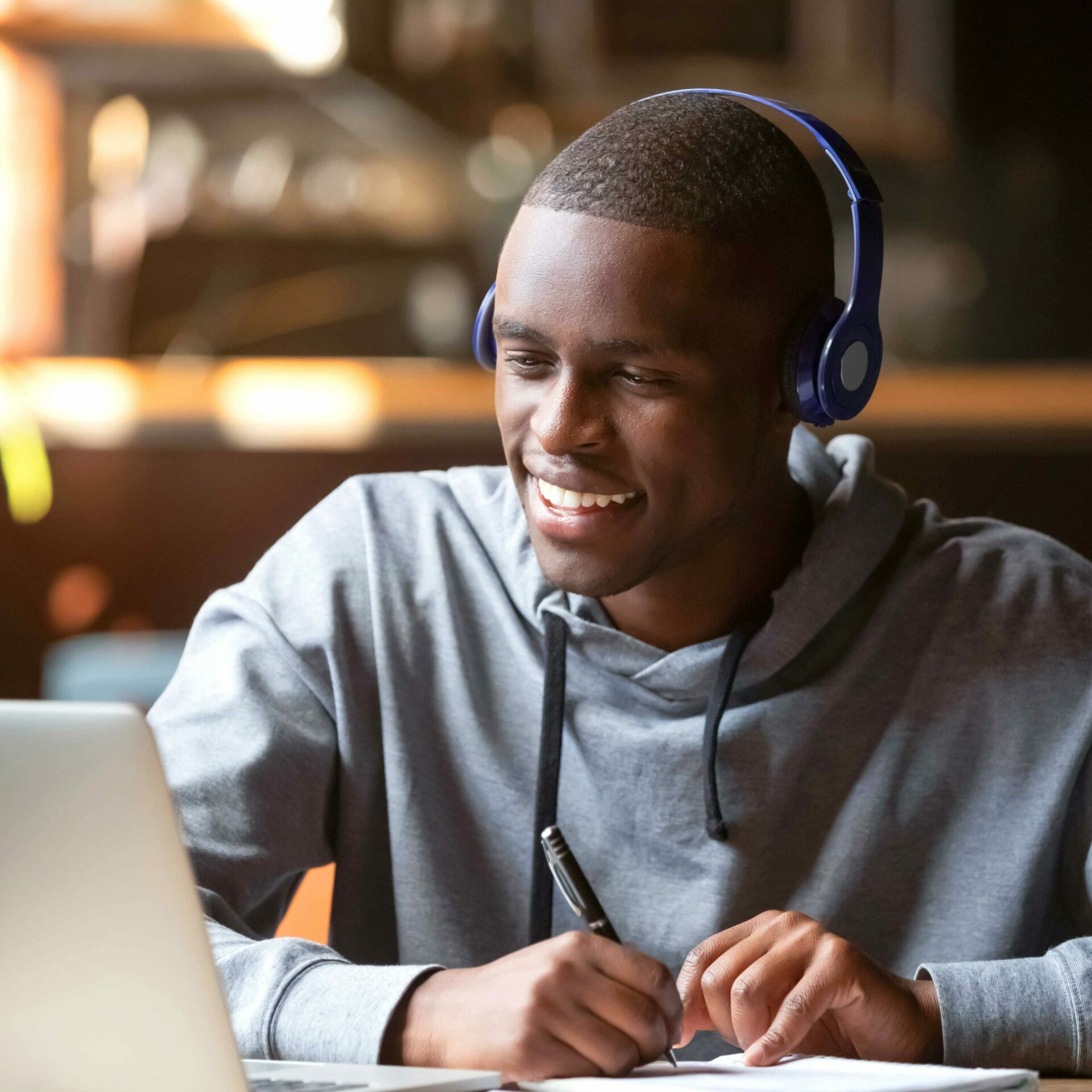 man smiling at computer while listening to an online class
