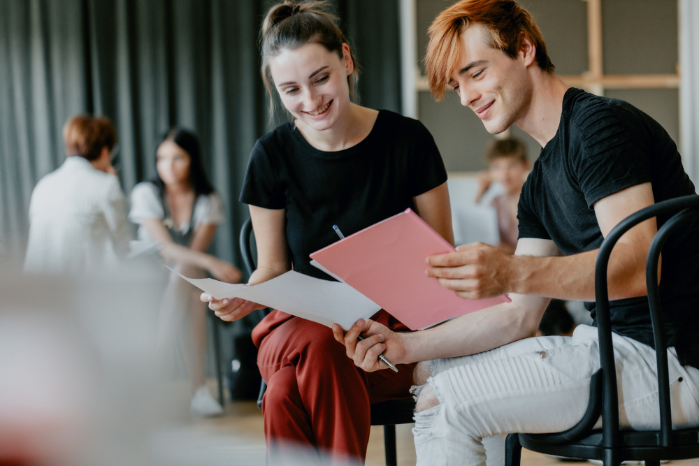 Teenage boy and girl reading the script together during theatre club classes