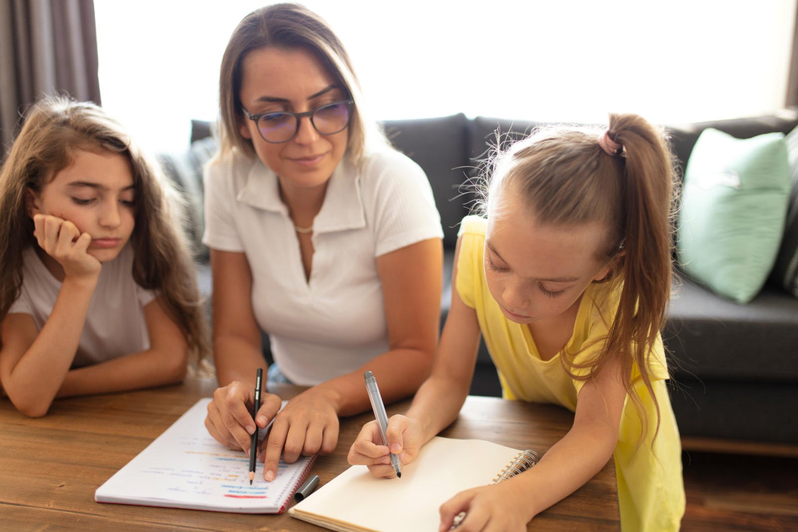 Mother helping daughters with homework.